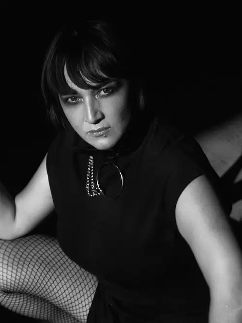 La DJ y productora chilena Valesuchi sentada en su estudio de producción musical en Santiago, rodeada de equipos electrónicos y decoraciones personales.