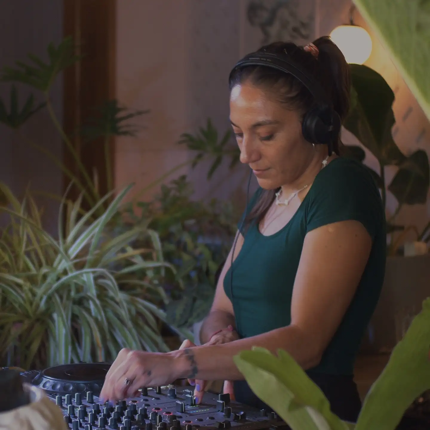 La DJ y productora chilena Valesuchi sentada en su estudio de producción musical en Santiago, rodeada de equipos electrónicos y decoraciones personales.