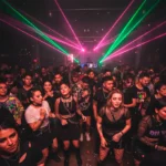 Público joven y diverso en una fiesta techno underground en Santiago, bailando bajo intensas luces láser de color rosa y verde.