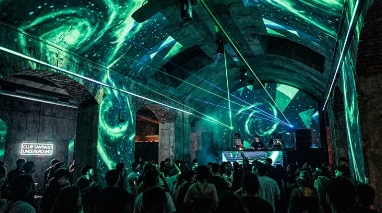 Los clubes de techno en Santiago que marcarán el pulso en 2026 10 Club de techno underground en Santiago de Chile con visuales cósmicos, láseres verdes y público bailando en una fiesta electrónica nocturna