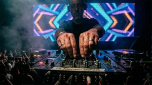 Primer plano de las manos de un DJ manipulando la mezcladora en una cabina oscura, guiando el viaje musical en fiesta de santiago de chile